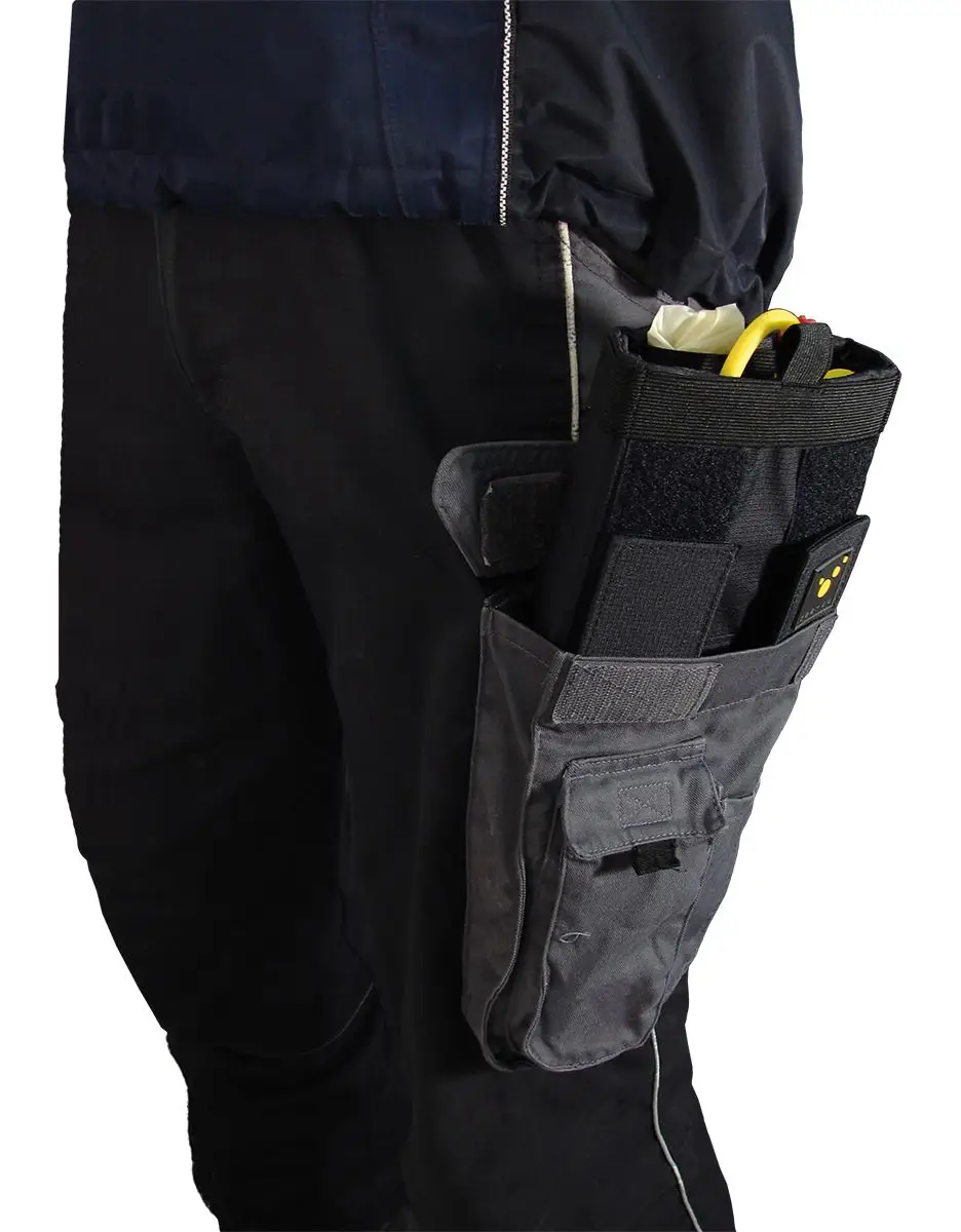 CARGO Pocket‑Holster am Oberschenkel: graue Cargo-Tasche mit schwarzem Einsatz an dunkler Arbeitshose, gefüllt mit einem schwarzen Holster, einem gelben Werkzeuggriff und einem weißen Einmalhandschuh